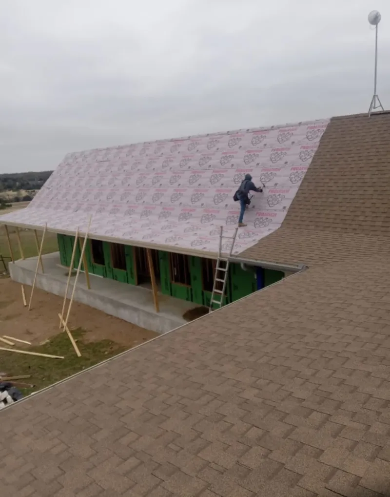 Worker preparing underlayment for a metal roof installation in Burnsville